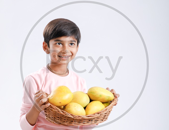 Indian Boy With Fresh Delicious Mangoes Basket on an Isolated White Background