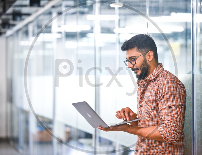 Focused Serious Working Indian IT professional Employee Young Man Student  On Laptop In Office Work Space