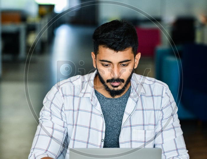 Focused Serious Working Indian Professional IT Employee Young Man  Student  On Laptop In Office Work Space