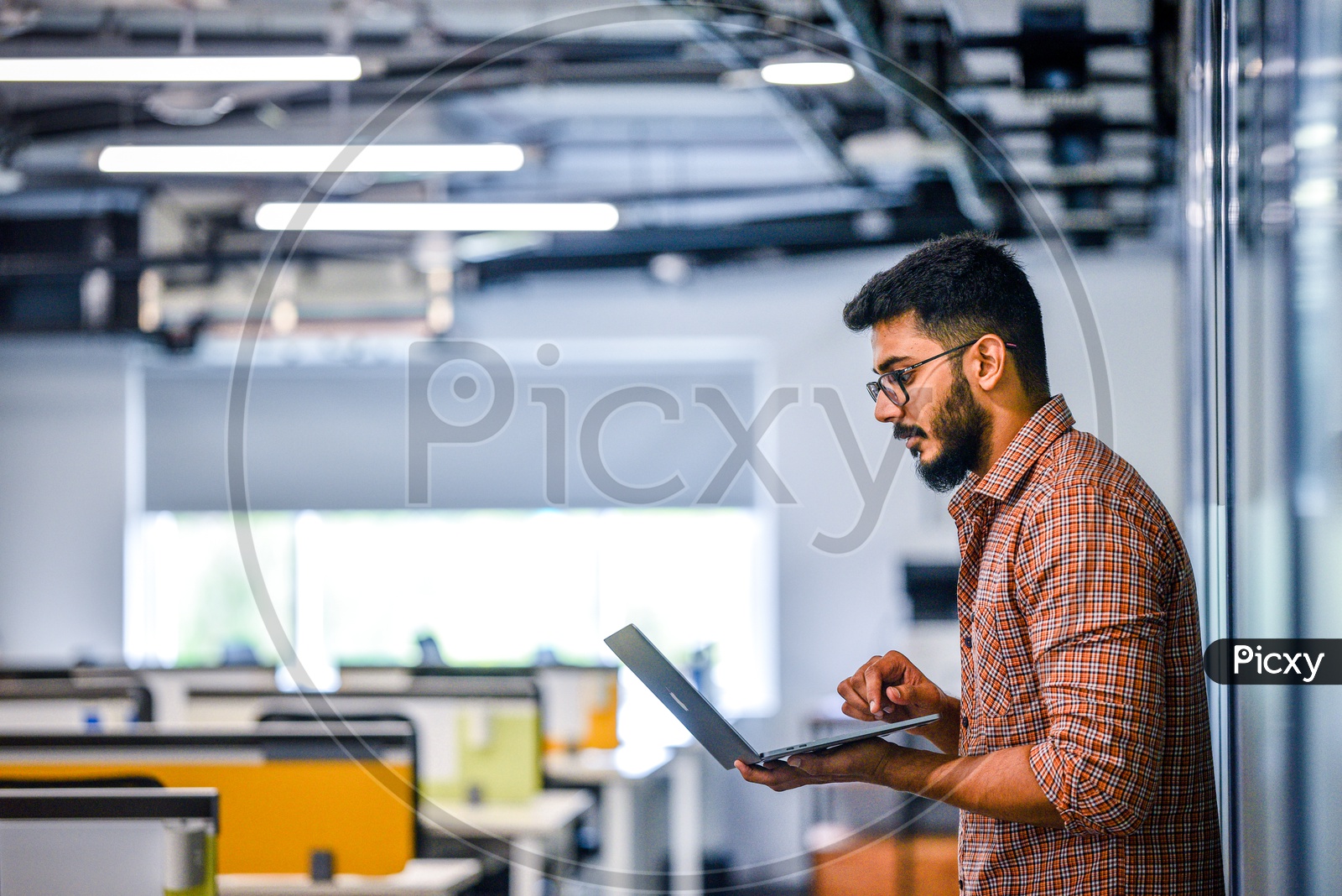 Focused Serious Working Indian IT Professonal young Man Student Employee  On Laptop In Office Work Space