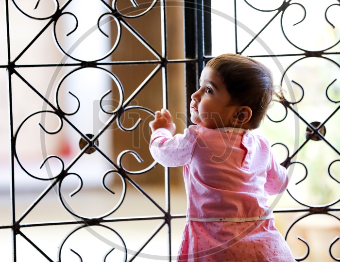 Cute Indian Baby Girl Standing at Grill Gate