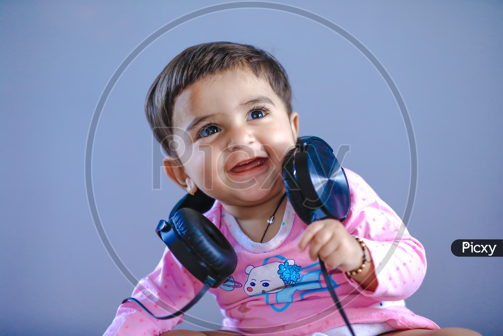 Cute Indian Baby Girl Listening Music  In Headphones With Cute Expressions On Face