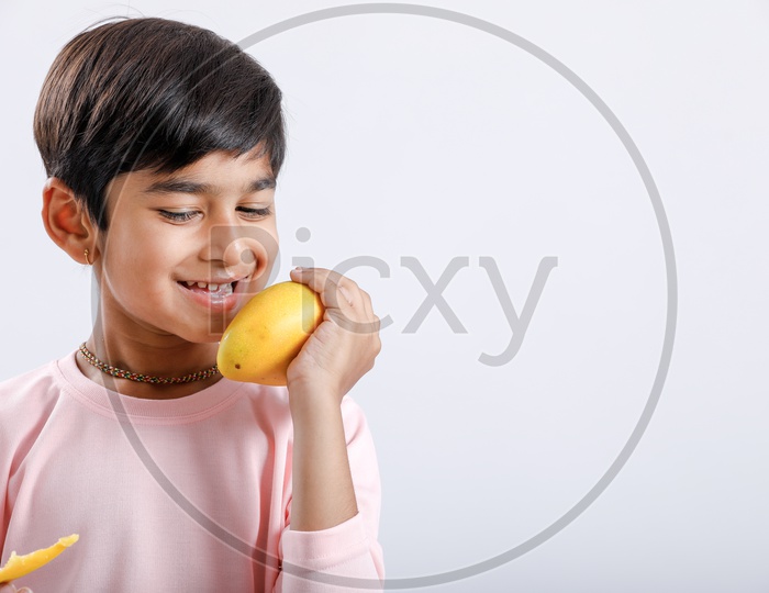 Indian Cute Boy  or  Asian Boy or kid Holding Mango With an Expression On an Isolated White Background