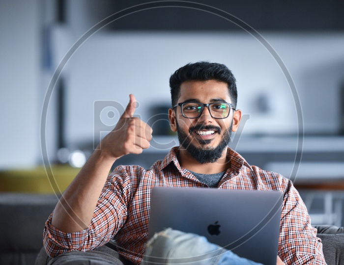 Confident smiling  Young Man or Indian Man Showing Thumb up Gesture While Working  on Laptop