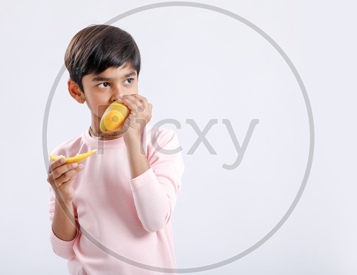 Indian Cute Boy  / Asian Boy or kid  Enjoying Eating  Mango  With an Expression On an Isolated White Background