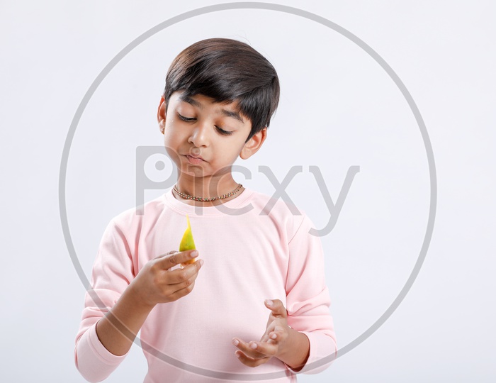 Indian Cute Boy  or  Asian Boy or kid Enjoy Eating  Mango With an Expression On an Isolated White Background