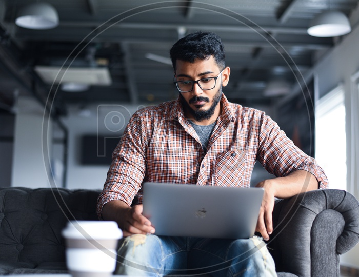 Focused Serious Working Young Man Or Indian Man On Laptop  in a Office Space