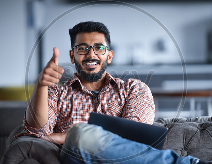 Confident smiling  Young Man or Indian Man Showing Thumb up Gesture While Working  on Laptop