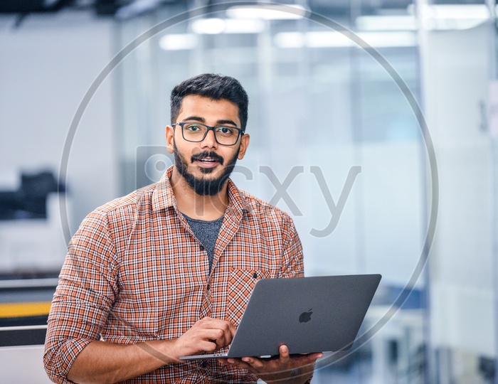 Young man or Indian man Happily Smiling Using Laptop in Working Space