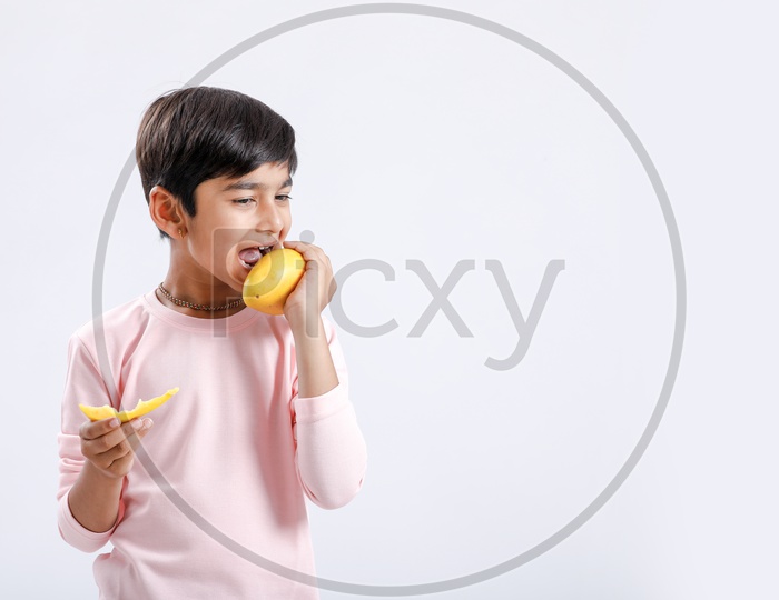 Indian Cute Boy  / Asian Boy or kid  Enjoying Eating  Mango  With an Expression On an Isolated White Background