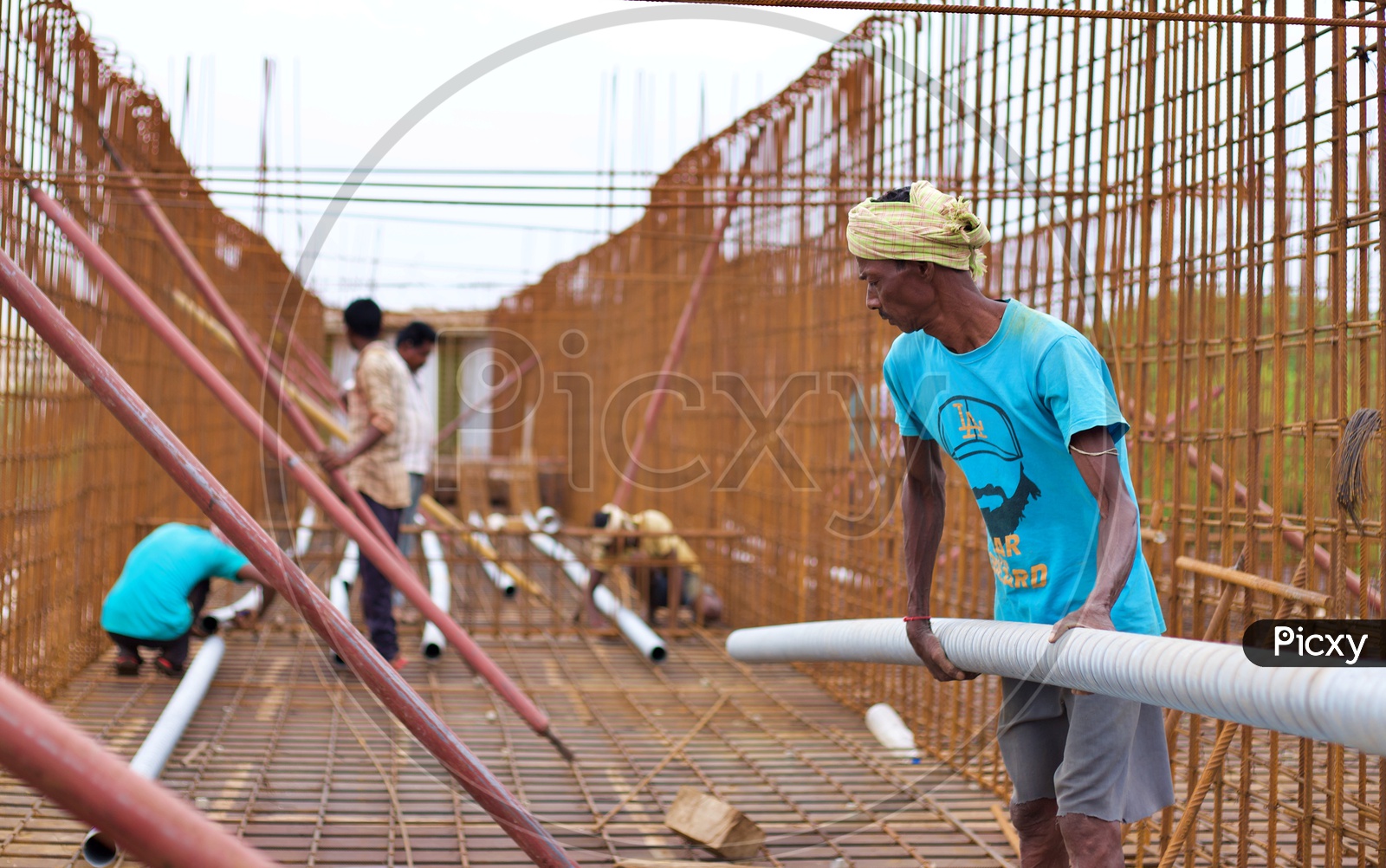 A construction worker carrying steel pipes.