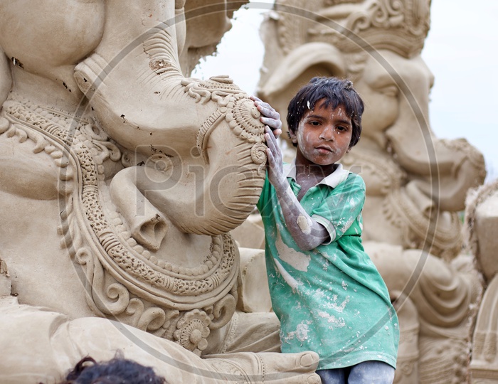 Kid standing beside a Ganesh statue.