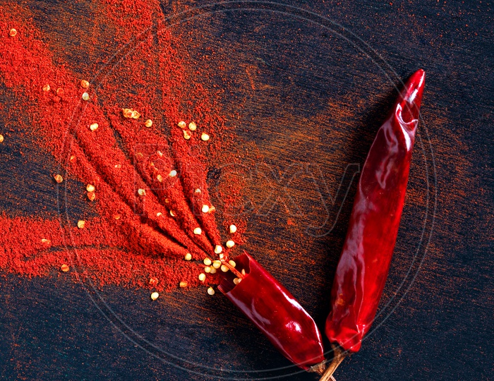 Red Chilli Powder With Chilli Flakes Composed To a Design On an Isolated Black Background