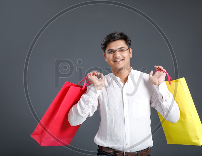 Young Man Or Indian man Carrying Shopping Bags and Posing Over an Isolated Black Background