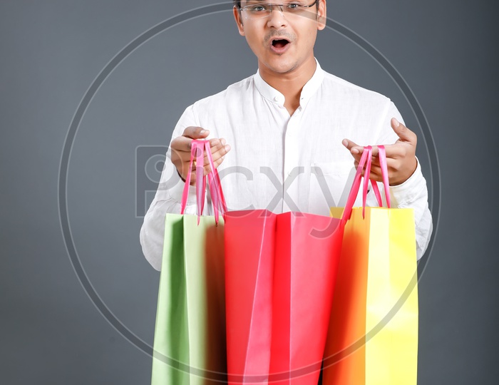 Young Man Carrying  Shopping Bags  And Posing Over an Isolated Black Background