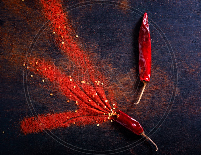 Red Chilli Powder With Chilli Flakes Composed To a Design On an Isolated Black Background