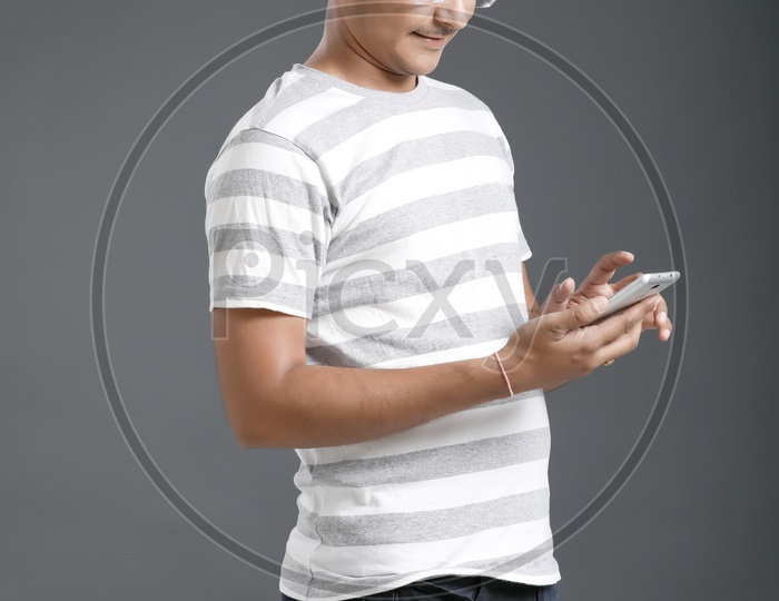 Young Man or Student Using  On Mobile Or Smart Phone Over an Isolated Black Background