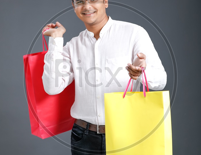 Young Man Or Indian man Carrying Shopping Bags and Posing Over an Isolated Black Background