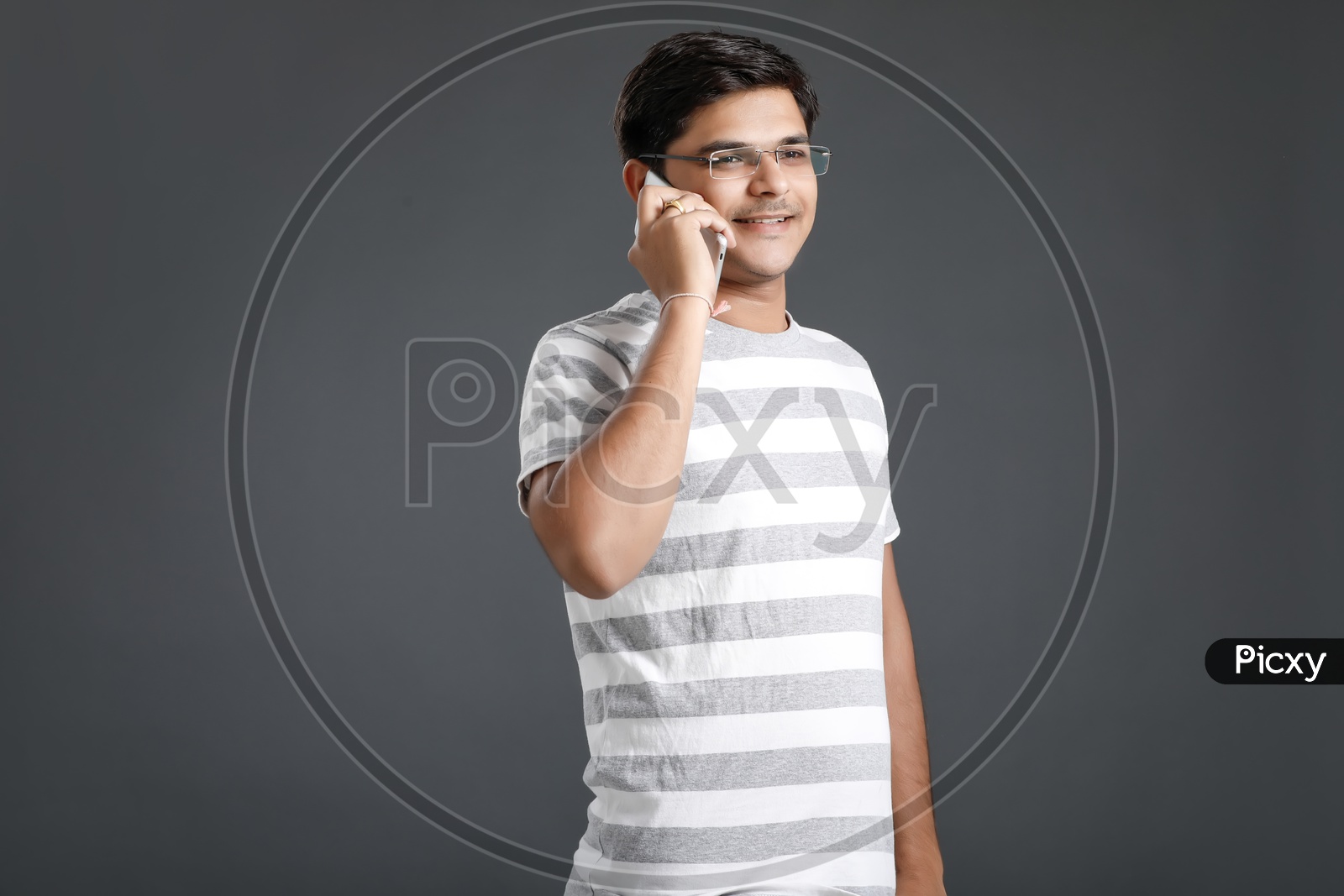 Young Man or Student Speaking On Mobile Or Smart Phone Over an Isolated Black Background