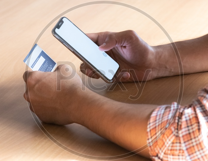 Online Payments Or Online Shopping  A Young Man Using Debit or Credit Card For Online Transaction or Payments in Smartphone or Mobile  Hands Closeup