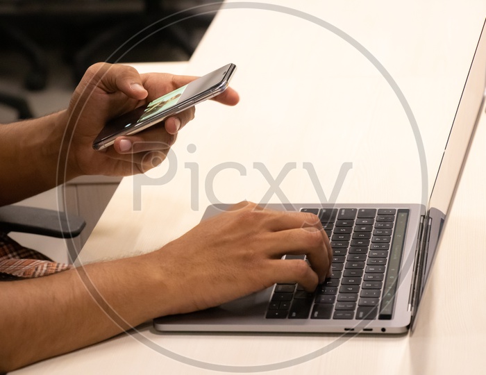 Young man Or Student Hands Using Mobile Or Smartphone While Working On Laptop  Closeup