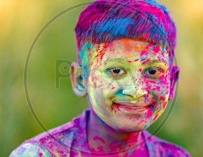 Indian Boy or Young Indian Boy  Playing Or Filled In Holi Colours Celebrating Holi Festival in Green Fields Background