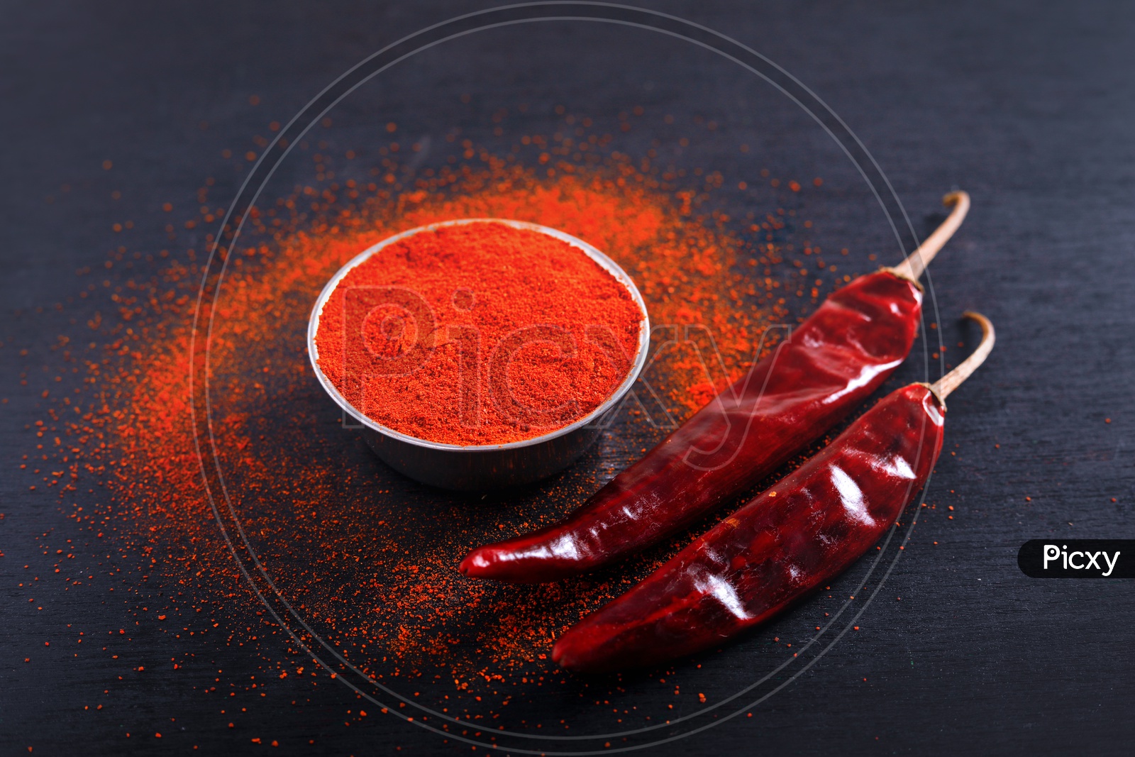Red Chilli Or Pepper Powder in a Bowl   And Sprinkled Around  On an Isolated  Black Background