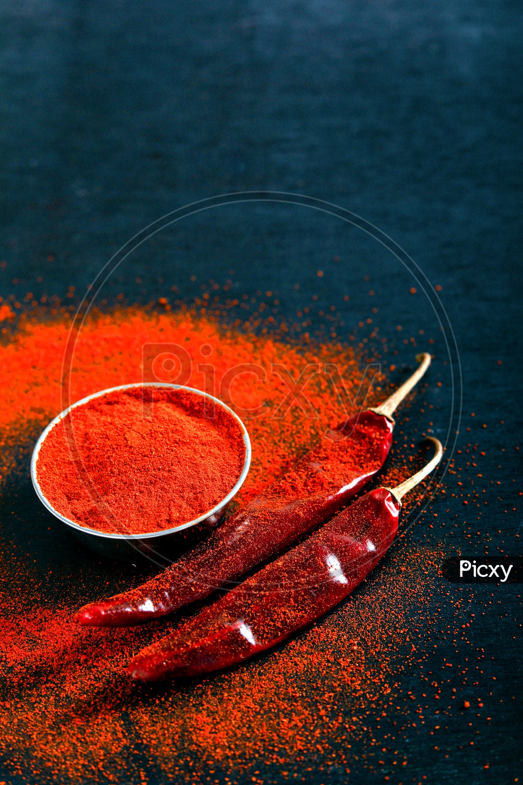 Red Chilli Or Pepper Powder in a Bowl   And Sprinkled Around  On an Isolated  Black Background