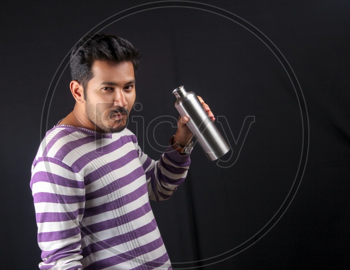 Young Indian Man Posing by Drinking Water   On an Isolated Black Background