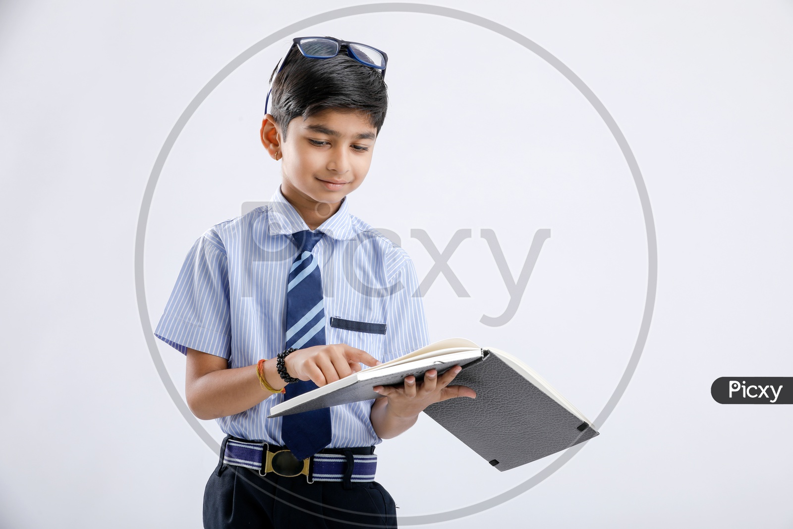 Indian Or Asian Boy Or Kid Or student in School Uniform  Wearing Spectacles And  Reading Book  Over an Isolated White Background