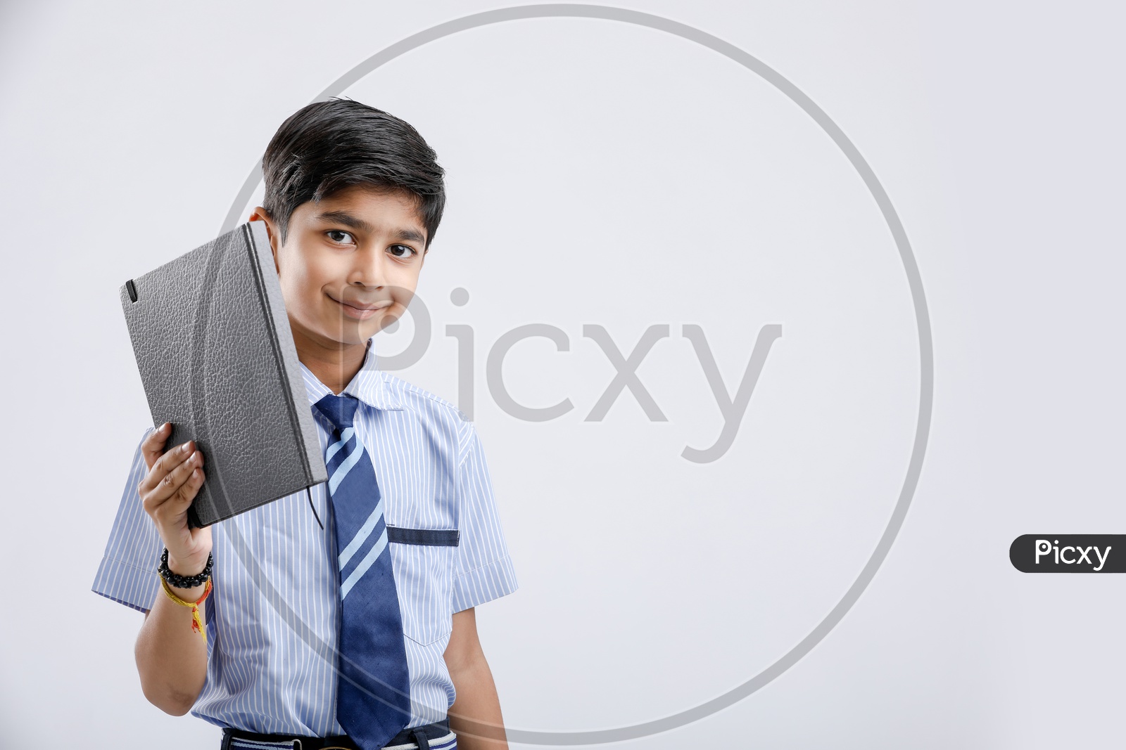 Cute Indian or Asian Kid Or Boy In School Uniform And Holding  Book   Over an Isolated White Background