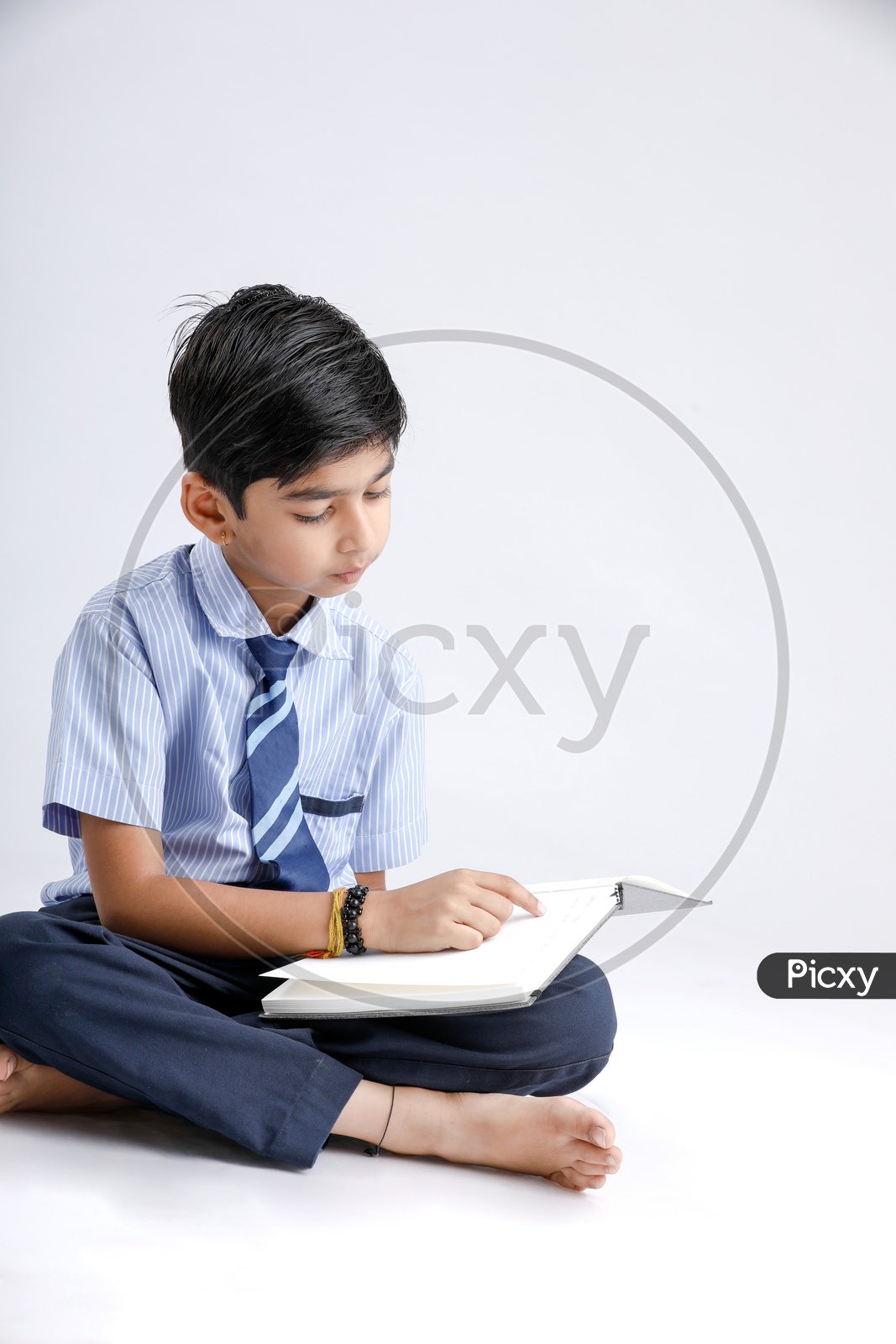 Indian or Asian Kid Or Boy Or Student  In School Uniform And Reading  Book Over an Isolated White Background