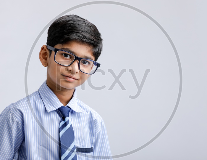 Cute Indian or Asian Kid Or Boy In School Uniform And Wearing Spectacles  Over an Isolated White Background