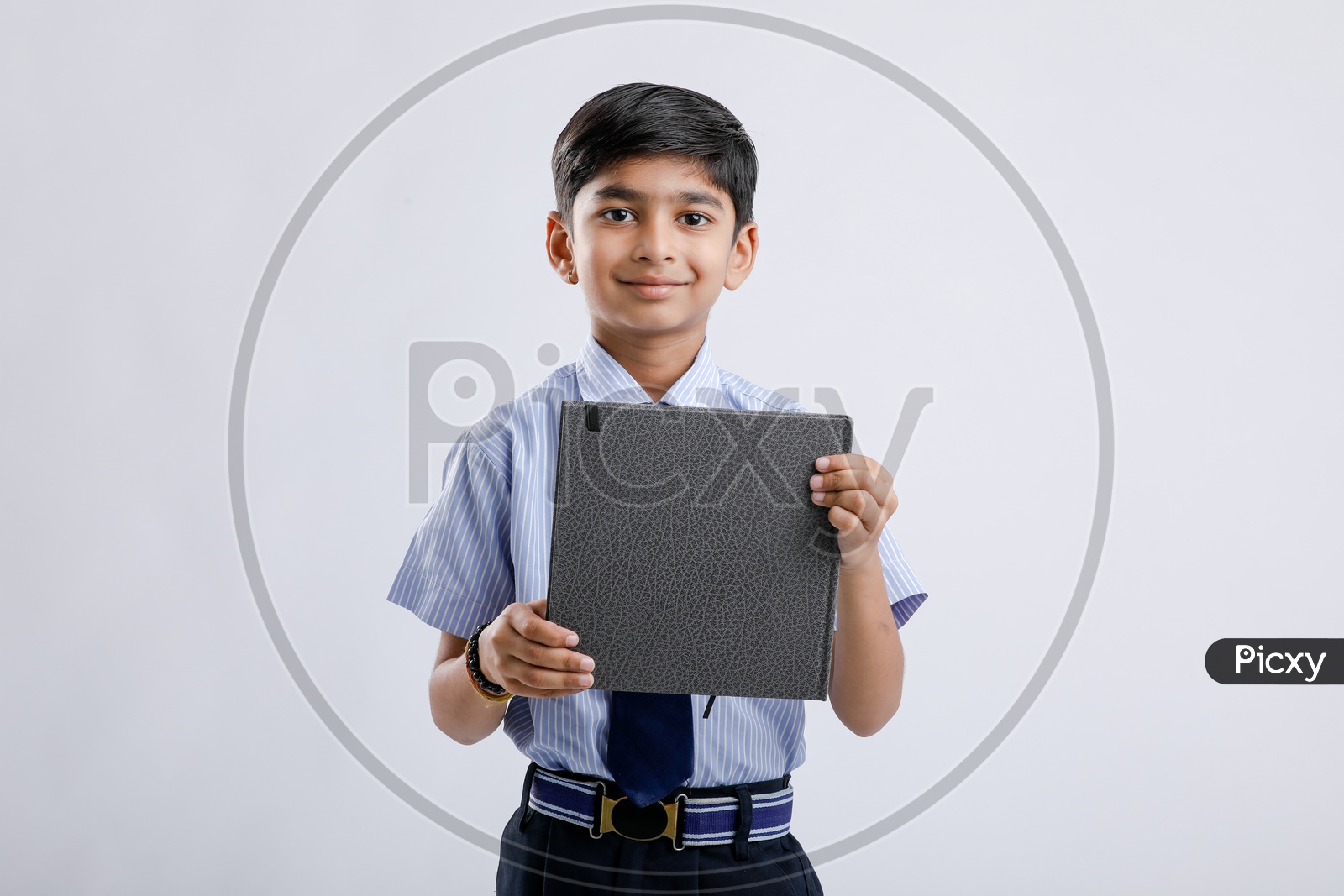 Indian or Asian Kid Or Boy  Or Student In School Uniform And  Holding  Book   Over an Isolated White Background