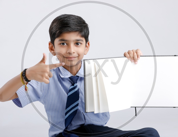 Cute Indian or Asian Kid Or Boy In School Uniform And Holding   Book   Over an Isolated White Background
