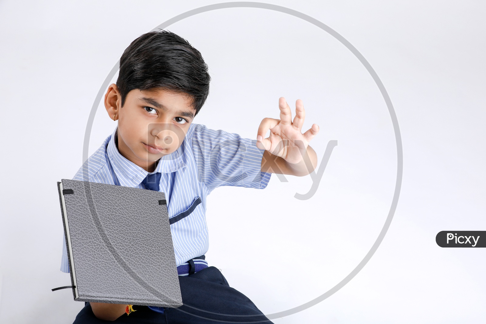 Indian Or Asian Kid Or Boy Or Student   In School Uniform  Holding a Book And Posing Over an Isolate White Background