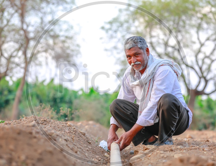 Indian Farmer Checking The Water Pipeline Or Tube In Agricultural Fields