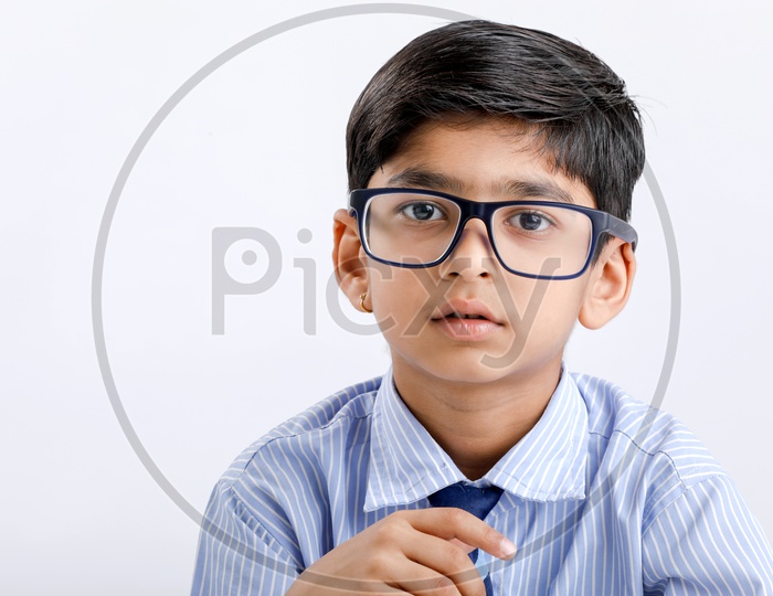 Indian or Asian School Kid Or Boy Wearing Uniform  And Posing With Spectacles  Over an Isolated White Background