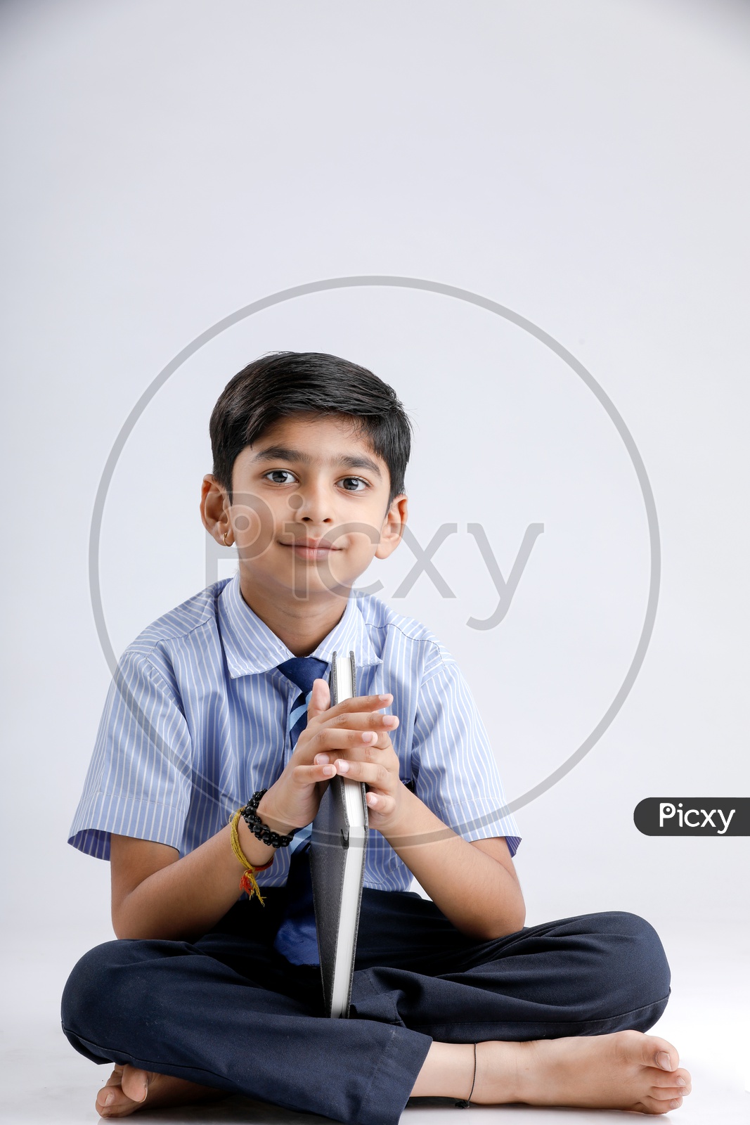 Indian or Asian Kid Or Boy Or Student  In School Uniform And Holding Book Over an Isolated White Background