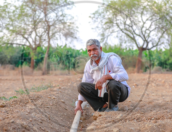 Indian Farmer Checking The Water Pipeline Or Tube In Agricultural Fields