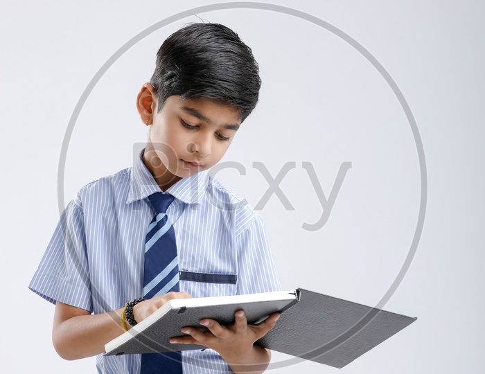 Indian or Asian Kid Or Boy Or Student  In School Uniform And Reading  Book Over an Isolated White Background