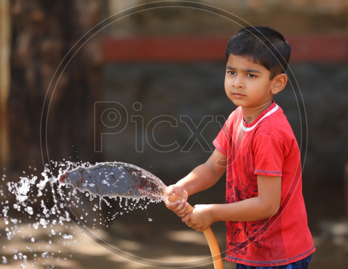 Indian Young Kid Or Child  Playing With Water Tube Water Splash