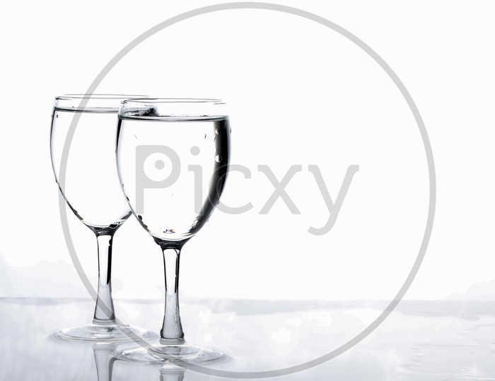 Wine Glasses Filled With Water and Water Splash On an Isolated White Background