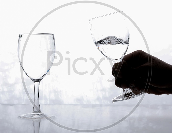 Hands Holding the Wine Glass Filled With Water For Toast on an Isolated White Background