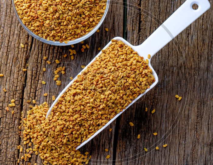 Fenugreek Seeds In a Glass Bowl  and In Scoop On an Wooden Background