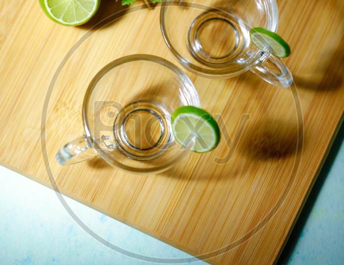 Empty Glass Tea Cups With Lemons And Holi Basil On Wooden  Table
