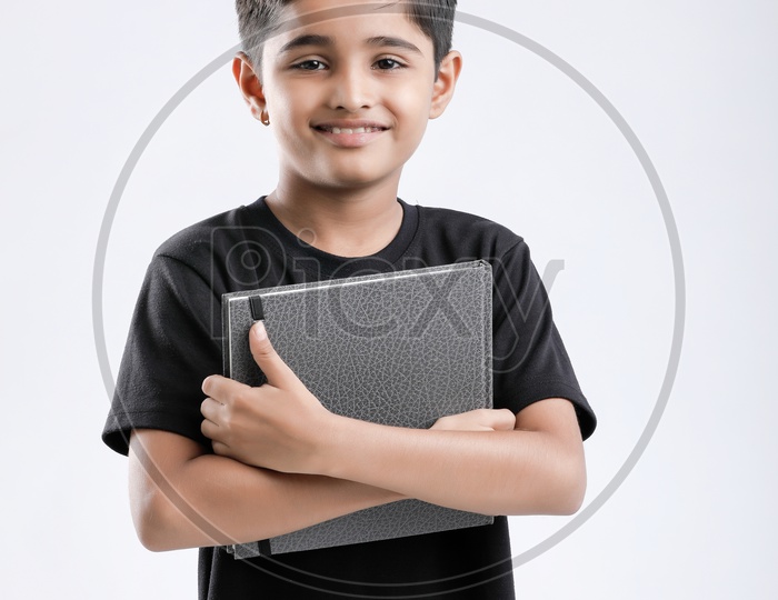 Indian or Asian Boy or Kid O r Child   Holding  Book  over an Isolated White Background