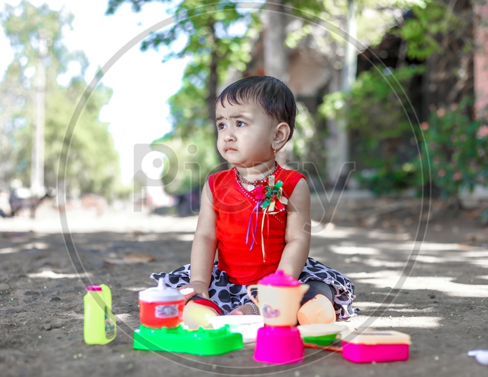 Cute Indian Baby Girl Child  Playing With Toys  In Outdoor Background