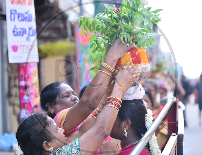 A Woman  Carrying Bonam or Bonalu On Her Head  in Queue Lines For Goddess Ujjaini Mahakali Temple During Bonalu Festival