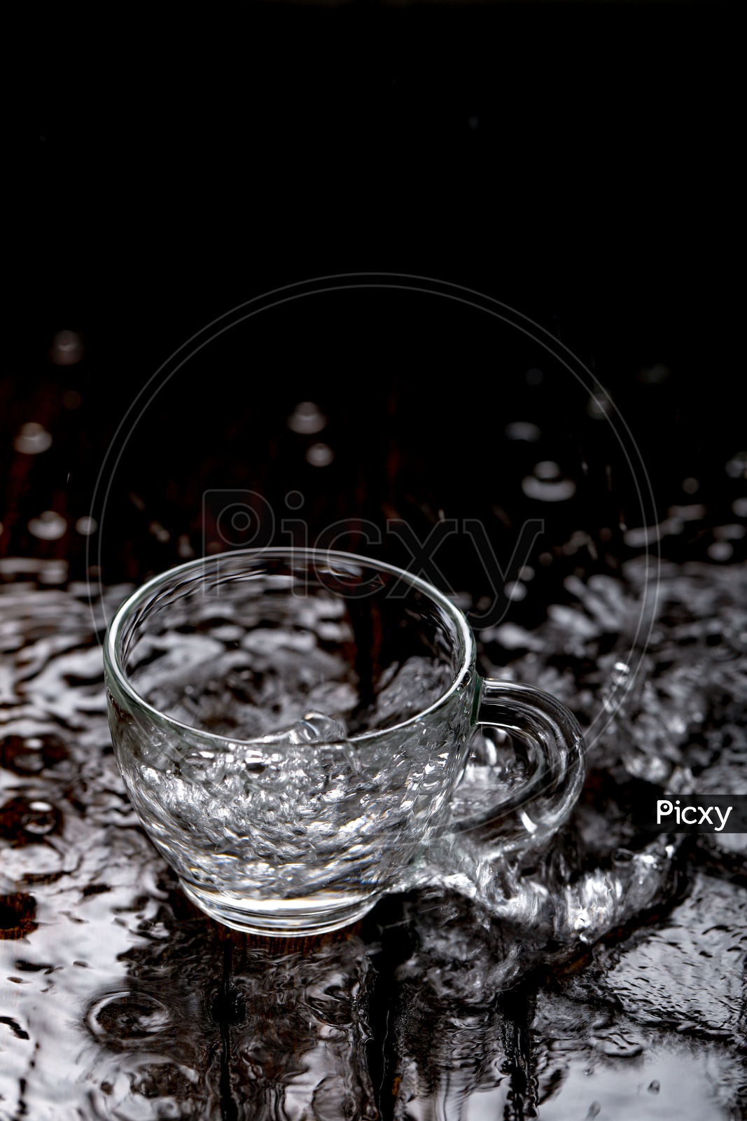 Empty Glass  Tea Cup Filling  With Water And Water Splash On an Wooden  Table Background
